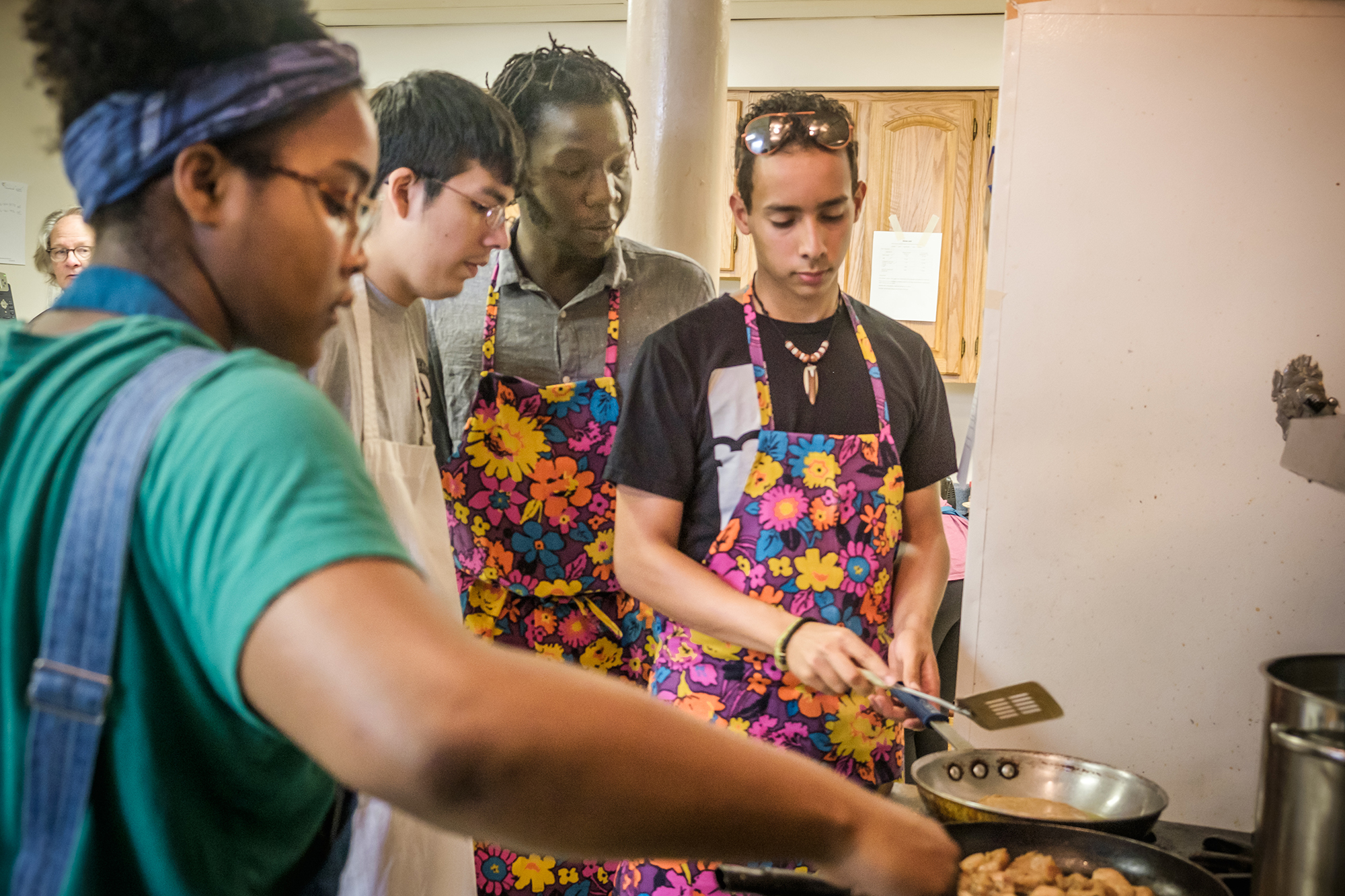 group of people cooking food in frying pans in a kitchen