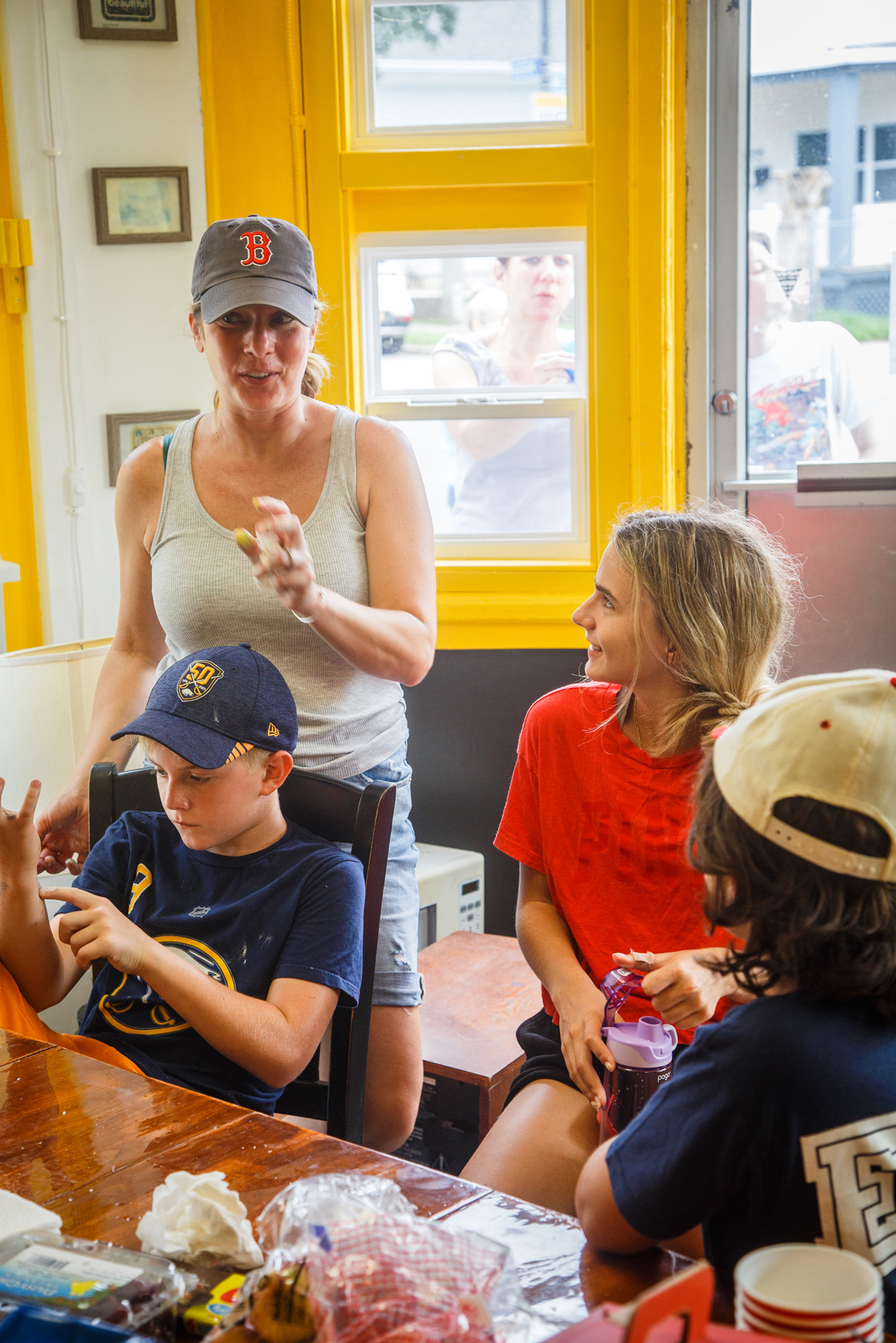 woman talking to a group of kids sitting around a table in a house